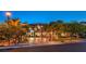 An opulent home with a circular driveway and lavish landscaping creates curb appeal at dusk at 3051 Traverse Creek Ln, Las Vegas, NV 89135
