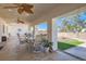 Covered patio featuring ceiling fans, stone tile flooring, a dining table, and views of the landscaped backyard at 3290 Vicki Ave, Las Vegas, NV 89139