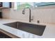 Close up view of a stainless steel kitchen sink with white countertops and tile backsplash at 356 Silva Pl, Henderson, NV 89011