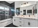Modern bathroom featuring dual sinks, white cabinets, black marble accent wall, and a glass-enclosed tub/shower combo at 3738 Falcon Springs Dr, Las Vegas, NV 89147