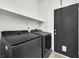 Modern laundry room features a black washer and dryer, and a black door with a pet door at 3738 Falcon Springs Dr, Las Vegas, NV 89147