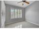 Neutral-toned bedroom featuring tile flooring, ceiling fan, and window with shutter blinds at 4905 Ocean Shores Way, Las Vegas, NV 89130