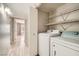 A laundry room equipped with a washer, dryer, wire shelving and a view into an adjacent bedroom at 4955 Lindell Rd # 130, Las Vegas, NV 89118