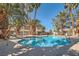 Community pool surrounded by tall palm trees with lounge chairs and tables for residents at 4955 Lindell Rd # 130, Las Vegas, NV 89118