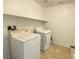 Functional laundry area with tile flooring, washer, dryer, and a convenient storage shelf at 5513 Silent Springs Dr, Las Vegas, NV 89122