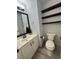 Clean half-bathroom featuring floating shelves, toilet, vanity and mirror at 5517 Bowerman Way, Las Vegas, NV 89130