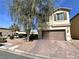Two-story home featuring a paver driveway and a mature tree providing shade in the front yard at 5634 Bishop Flowers St, Las Vegas, NV 89130