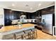 Kitchen island with granite countertop and seating, dark cabinets, stainless steel appliances and tile backsplash at 5634 Bishop Flowers St, Las Vegas, NV 89130