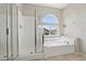 Bright bathroom featuring a soaking tub under an arch window and glass enclosed shower at 5655 Danforth Ave, Las Vegas, NV 89141