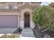 Inviting front entrance with an arched doorway, desert landscaping, and an attached two-car garage at 5655 Danforth Ave, Las Vegas, NV 89141