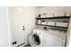 Bright laundry room features a washer, dryer, shelves, and door to the side yard at 5929 Royal Castle Ln, Las Vegas, NV 89130