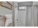 Close-up of a tiled shower with a shower curtain, and a sign reading, 