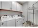 Well-equipped laundry room with modern washer, dryer, and overhead cabinets for storage at 5957 Olivine Falls Ave, Las Vegas, NV 89130