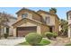 Well-manicured two-story house featuring a two-car garage and desert landscaping at 6390 Whispering Clouds Ct, Las Vegas, NV 89141