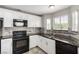 Modern kitchen featuring white cabinets, black appliances, and stone backsplash at 6428 Yarmouth Dr, Las Vegas, NV 89108