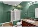 Modern bathroom with green walls, a glass shower, and a granite countertop at 7817 Safari Ln, Las Vegas, NV 89129