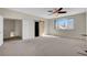 Spacious bedroom with neutral carpeting, ceiling fan, barn door, and a view overlooking the neighborhood at 7817 Safari Ln, Las Vegas, NV 89129