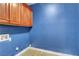 Blue laundry room features upper wood cabinets and tile flooring at 7817 Safari Ln, Las Vegas, NV 89129