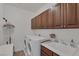 Well-lit laundry room features a washer, dryer, utility sink, and upper cabinets at 7872 Regency Park St, Las Vegas, NV 89149