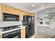 Efficient kitchen featuring light wood cabinets, black appliances, and tile countertops at 805 Dana Hills Ct # 104, Las Vegas, NV 89134