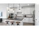 This open kitchen features stainless appliances, dark countertops, pendant lights, and seating at the island at 84 Via Franello, Henderson, NV 89011