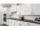 The bright kitchen features white cabinets, stainless steel appliances, dark countertops, and modern backsplash at 84 Via Franello, Henderson, NV 89011