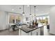 Modern kitchen boasts stainless steel appliances, pendant lighting, an island, and an adjacent dining area and living room at 84 Via Franello, Henderson, NV 89011