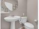 Cozy half bathroom featuring a pedestal sink, round mirror, and toilet with neutral wall color at 946 Belton Lake Ave, North Las Vegas, NV 89086