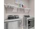 Well-organized laundry room with modern, stainless steel washer and dryer units and convenient shelving at 946 Belton Lake Ave, North Las Vegas, NV 89086