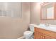 Cozy bathroom features wood cabinets, a mirror, toilet, and natural lighting from a window at 9740 Floweret Ave, Las Vegas, NV 89117