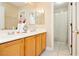 Well-lit bathroom with double sinks, wooden cabinets, and a shower at 977 Trackers Glen Ave, Henderson, NV 89015