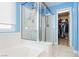 Blue bathroom features a glass-enclosed shower, a soaking tub, and ample storage space, blending functionality with style at 977 Trackers Glen Ave, Henderson, NV 89015