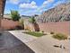 Enclosed backyard featuring desert landscaping, a small grassy area, brick pavers, and a backdrop of natural rock formation at 1063 Upper Springs St, Henderson, NV 89002