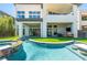 A refreshing swimming pool with bar stools, waterfall, and hot tub next to a modern home at 10748 Steel Ridge Ct, Las Vegas, NV 89135