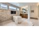 Modern bathroom with a soaking tub, stone accent wall, and dual windows for natural light at 10748 Steel Ridge Ct, Las Vegas, NV 89135