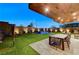 Beautiful backyard with a well-lit pool and spa, featuring a dining table and chairs and manicured landscaping at 1181 Calle De Luz, Henderson, NV 89012
