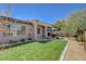 Backyard with a green lawn, desert landscaping, patio area, and mature trees for privacy at 12 Kennesaw Rd, Henderson, NV 89052