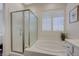 Bathroom featuring a soaking tub with chrome fixtures, a glass-enclosed shower, and shuttered window at 12 Kennesaw Rd, Henderson, NV 89052