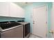 Laundry room with modern washer and dryer, built-in white cabinets, and tile flooring at 190 Channel Dr, Henderson, NV 89002