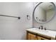 Powder room with a wood vanity, round mirror, and sleek black hardware at 2046 Waverly Cir, Henderson, NV 89014
