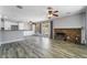 Spacious living room featuring wood-look tile flooring, white trim, ceiling fans, and a cozy fireplace with brick surround at 2046 Waverly Cir, Henderson, NV 89014