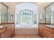 Bathroom featuring a soaking tub surrounded by cabinets and countertops and a privacy glass window at 308 Kingsclear Ct, Las Vegas, NV 89145