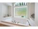 Close up of a bright bathtub with chrome fixtures with a decorative privacy glass window behind it at 308 Kingsclear Ct, Las Vegas, NV 89145