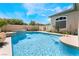 A serene backyard pool with a gentle waterfall feature, set amidst lush landscaping and privacy walls at 308 Kingsclear Ct, Las Vegas, NV 89145