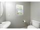 Neutral toned powder room with window, toilet and white pedestal sink at 3367 Popcorn Flower St, Las Vegas, NV 89117