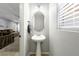 Stylish powder room with a pedestal sink, oval mirror and soft gray color palette at 3367 Popcorn Flower St, Las Vegas, NV 89117