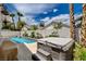 Backyard with a covered hot tub, beautiful blue pool, and surrounding tropical landscaping under a cloudy sky at 4334 Libbiano Ct, Las Vegas, NV 89141