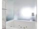 Close up of a modern white soaker bathtub with jacuzzi jets and frosted glass shower wall at 4381 W Flamingo Rd # 1102/1104, Las Vegas, NV 89103