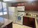 Well-lit kitchen features white appliances, dark wood cabinets, and speckled granite countertops at 4965 Indian River Dr # 101, Las Vegas, NV 89103
