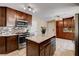 Modern kitchen featuring an island, granite countertops, stainless steel appliances, and tile flooring at 6117 Foxcroft Ave, Las Vegas, NV 89108